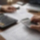 A person reviewing financial documents with a calculator and a laptop.